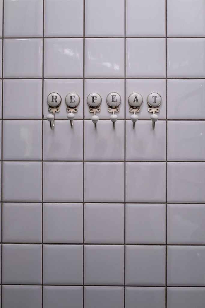 close up of towel hangers with letters attached to the tiles in a bathroom